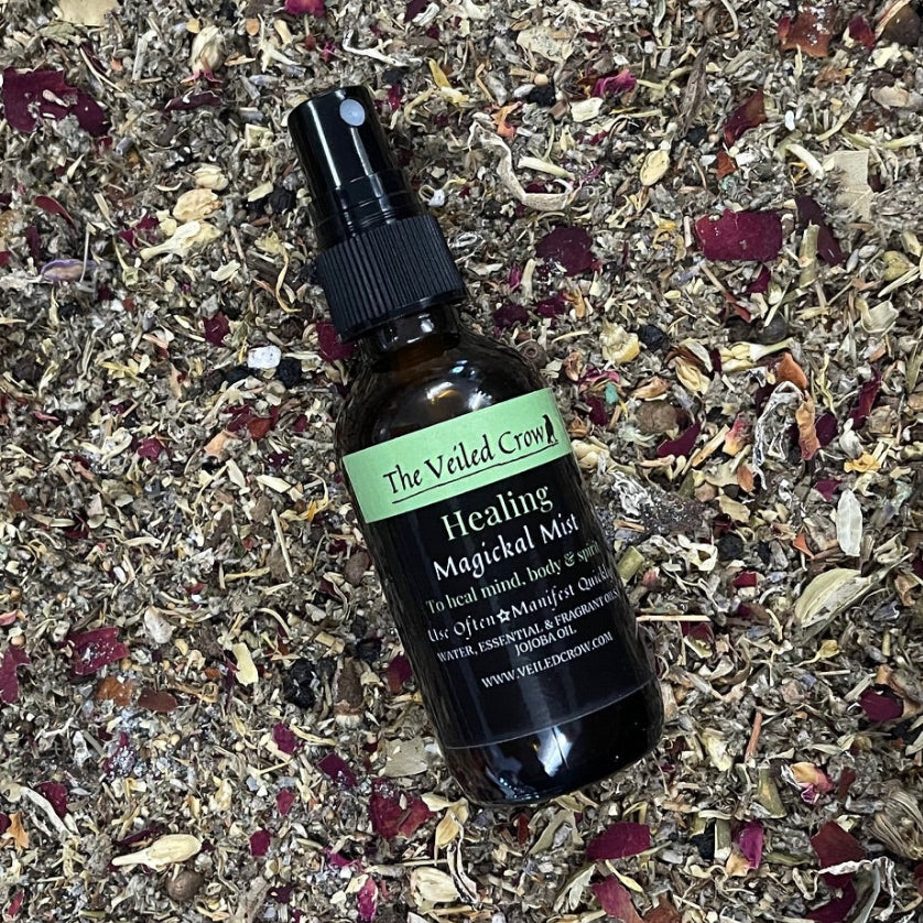 Bottle of Healing Magickal Mist on a bed of dried herbs and spices on a wooden surface.